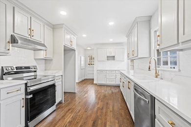 Kitchen featuring white cabinetry, sink, and appli