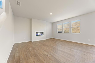 Unfurnished living room featuring visible vents, baseboards, a glass covered fireplace, recessed lighting, and light wood-style flooring