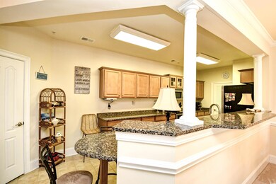 Kitchen with ornate columns, freestanding refrigerator, a breakfast bar, dark stone countertops, and a peninsula