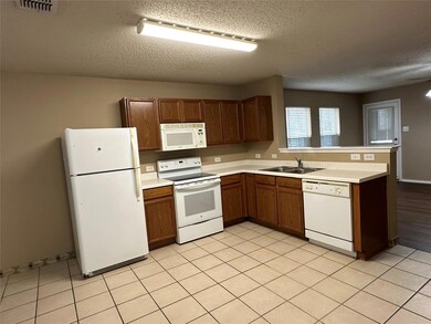 Kitchen featuring visible vents, light countertops, a peninsula, white appliances, and a sink