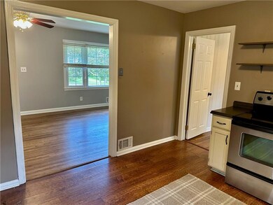 Kitchen featuring electric range, dark wood-style flooring, white cabinetry, and ceiling fan