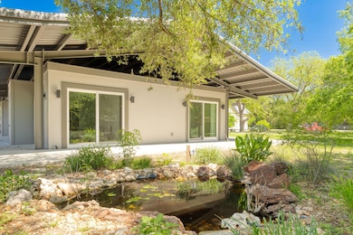 Back of house with a small pond and stucco siding