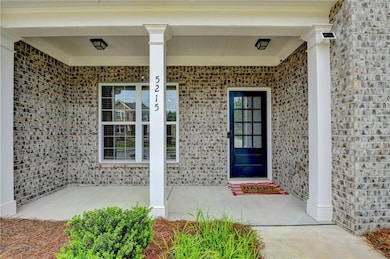 Property entrance featuring covered porch and brick siding