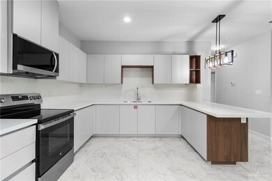 Kitchen featuring pendant lighting, kitchen peninsula, white cabinets, and appliances with stainless steel finishes