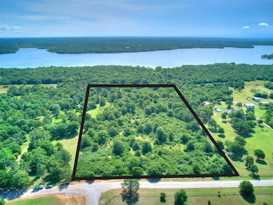 Aerial view of property and surrounding area with a large body of water, a heavily wooded area, and property parcel outlined