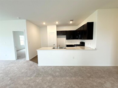 Kitchen featuring light countertops, black range with gas cooktop, light colored carpet, a peninsula, and dark cabinetry