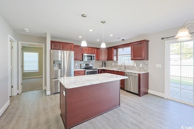 Kitchen featuring reddish brown cabinets, stainless steel appliances, decorative backsplash, light stone counters, and recessed lighting