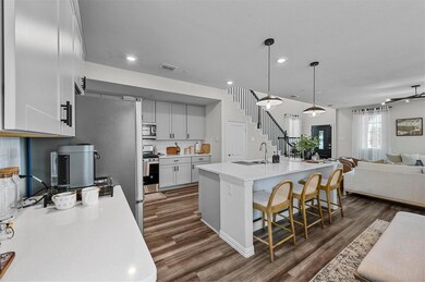 Kitchen with a kitchen breakfast bar, sink, dark hardwood / wood-style flooring, appliances with stainless steel finishes, and a kitchen island with sink