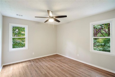 Empty room with ceiling fan, wood-type flooring, and a textured ceiling