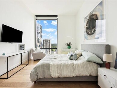 Bedroom featuring expansive windows, light wood-t