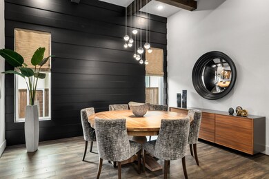 Chic, modern dining area designed for everyday living and memorable gatherings. Features a dramatic black accent wall with sleek shiplap paneling and a stunning custom contemporary orb chandelier, creating a bold, intimate atmosphere. This gorgeous room also features the rich flooring and elegant woven Roman shades.