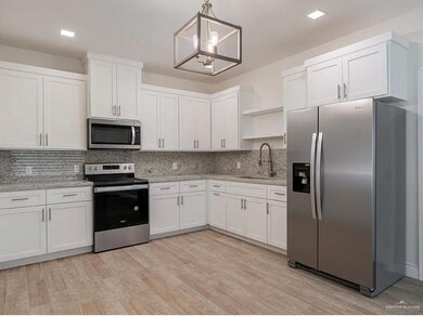 Kitchen featuring open shelves, a sink, appliances with stainless steel finishes, white cabinetry, and a notable chandelier