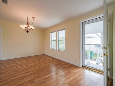 Unfurnished room featuring light wood finished floors, crown molding, and a chandelier