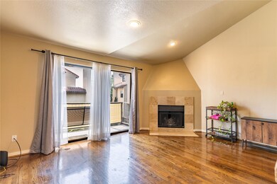 Living room featuring wood finished floors, a textured ceiling, a fireplace, vaulted ceiling, and recessed lighting