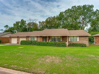 Single story home featuring a front lawn, brick siding, driveway, and a garage