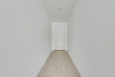 Corridor featuring light wood-type flooring and baseboards