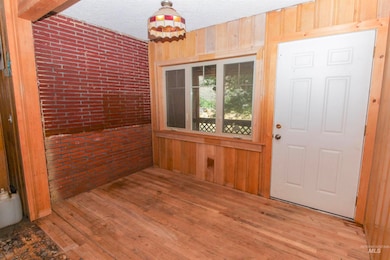 Foyer with wooden walls, wood-type flooring, and a textured ceiling