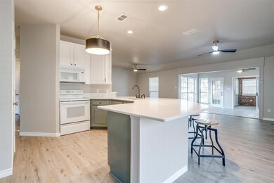 Kitchen featuring white cabinets, a kitchen breakfast bar, pendant lighting, light hardwood / wood-style floors, and white appliances