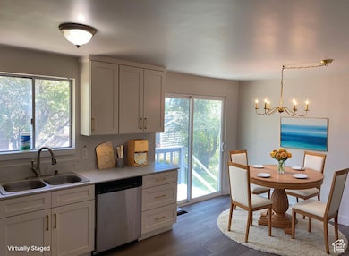 Kitchen with stainless steel dishwasher, healthy amount of natural light, dark wood-type flooring, and white cabinets