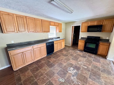 Kitchen with baseboards, a sink, dark countertops,
