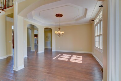 Entertain guests in style in this lovely formal dining room, featuring a tiered octagonal tray ceiling, sunny transom window, gently arching entryways, and light fixture with ceiling medallion that echoes the fixture in the adjacent foyer.