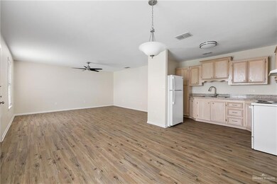 Kitchen with stove, light brown cabinetry, light countertops, visible vents, and freestanding refrigerator