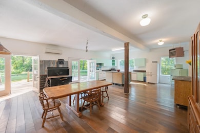 Dining room with beam ceiling, light wood finished floors, and an AC wall unit