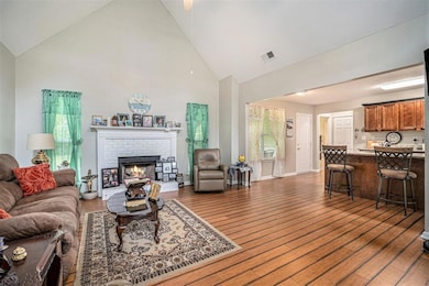 THE LIVING ROOM HAS A BRICK FIREPLACE WITH GAS LOGS AND IS OPEN TO THE KITCHEN.