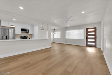 Unfurnished living room featuring ceiling fan, lig