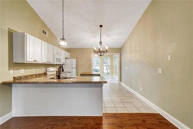 Kitchen with white appliances, lofted ceiling, a peninsula, white cabinets, and pendant lighting
