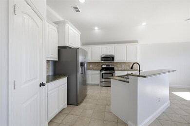 Kitchen featuring white cabinetry, dark stone countertops, stainless steel appliances, light tile patterned flooring, and backsplash