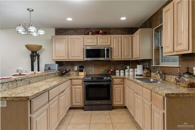 Kitchen featuring pendant lighting, light brown cabinetry, range with electric cooktop, a notable chandelier, and sink