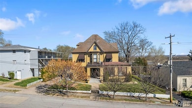 View of front facade featuring roof with shingles and a balcony