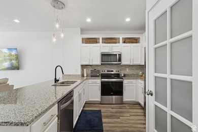 Kitchen with white cabinetry, stainless steel appliances, a peninsula, pendant lighting, and recessed lighting