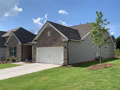 View of front of property with a front yard, brick siding, driveway, and a garage