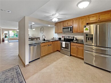 Kitchen with stainless steel appliances, brown cabinetry, open floor plan, a ceiling fan, and light tile patterned floors