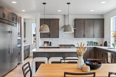 Kitchen with dark brown cabinets, built in appliances, pendant lighting, and recessed lighting