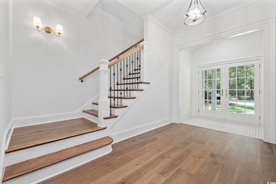 Foyer with hardwood / wood-style floors, crown molding, french doors, and stairs