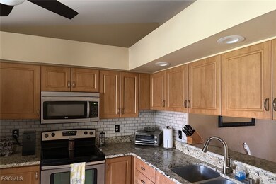 Kitchen with stainless steel appliances, dark stone counters, brown cabinets, tasteful backsplash, and a ceiling fan