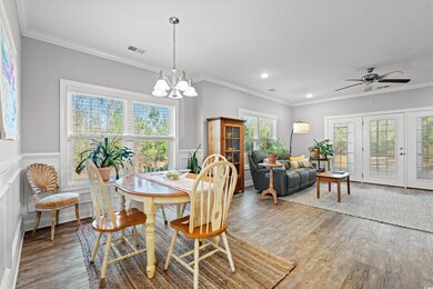Dining room with a wainscoted wall, ornamental molding, wood finished floors, and visible vents