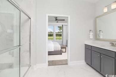 Full bathroom featuring a marble finish shower, vanity, marble look tile flooring, ceiling fan, and baseboards