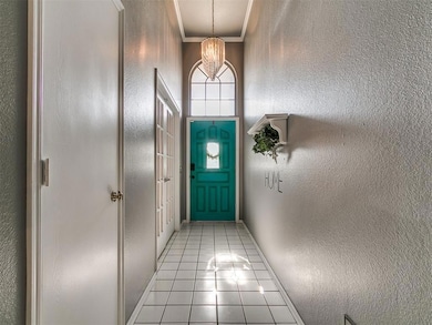 Entryway with light tile patterned floors, a textured wall, a chandelier, baseboards, and ornamental molding