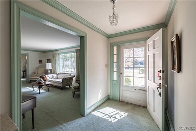 Entryway featuring light colored carpet, crown molding, and a notable chandelier