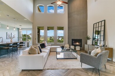 Living area featuring a fireplace, a towering ceiling, and a ceiling fan