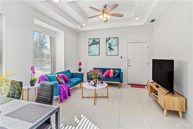 Tiled living room featuring a tray ceiling and ceiling fan