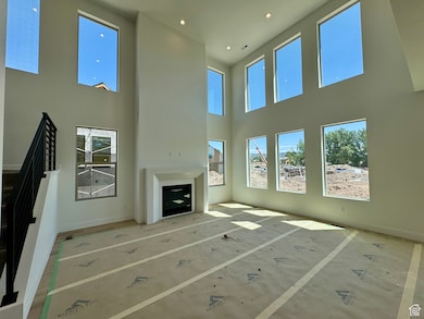 Unfurnished living room featuring a towering ceiling and recessed lighting