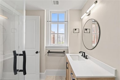 Bathroom with vanity, marble finish floors, healthy amount of natural light, and a stall shower