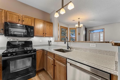 The kitchen features beautiful hardwood floors that flow throughout the main level, complemented by generous granite countertops, a convenient breakfast bar, and sleek black appliances.