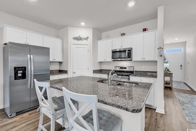 Kitchen with light wood-style flooring, white cabi