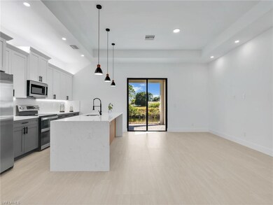 Kitchen featuring appliances with stainless steel finishes, decorative light fixtures, recessed lighting, white cabinets, and light stone counters